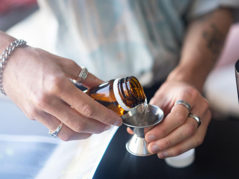 A man pouring alcohol with a cocktail making kit.